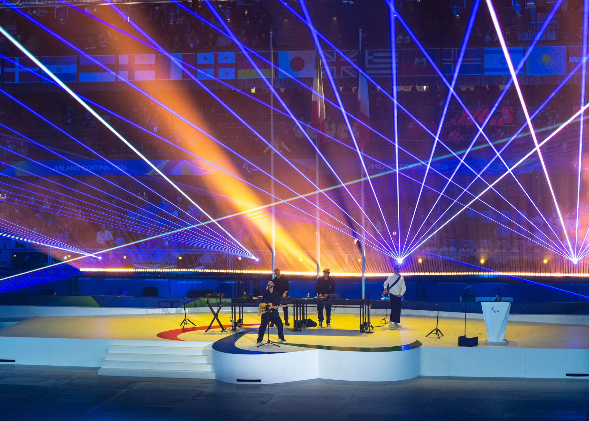 Bändi esiintymässä lavalla värikkäiden valonsäteiden loisteessa.